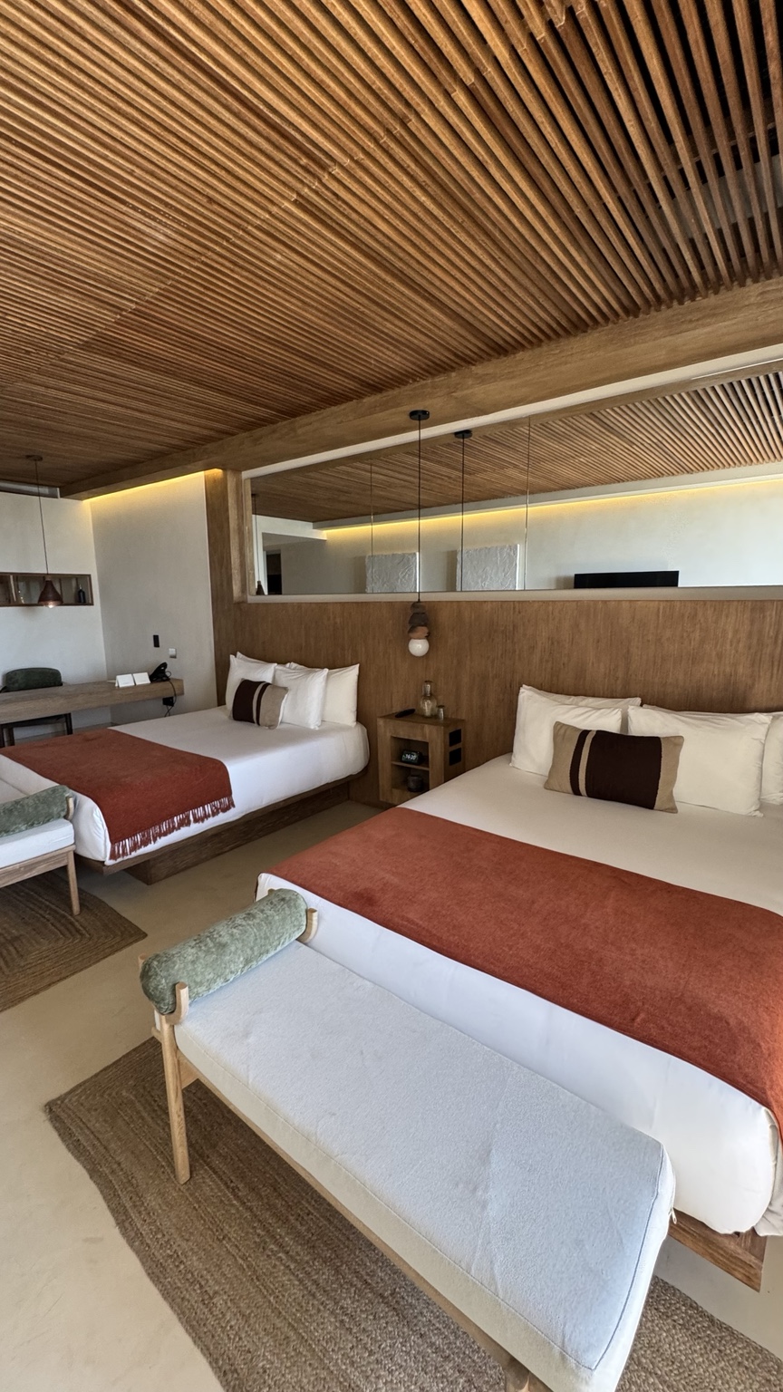A warm hotel room with a wood-slat ceiling and natural finishes