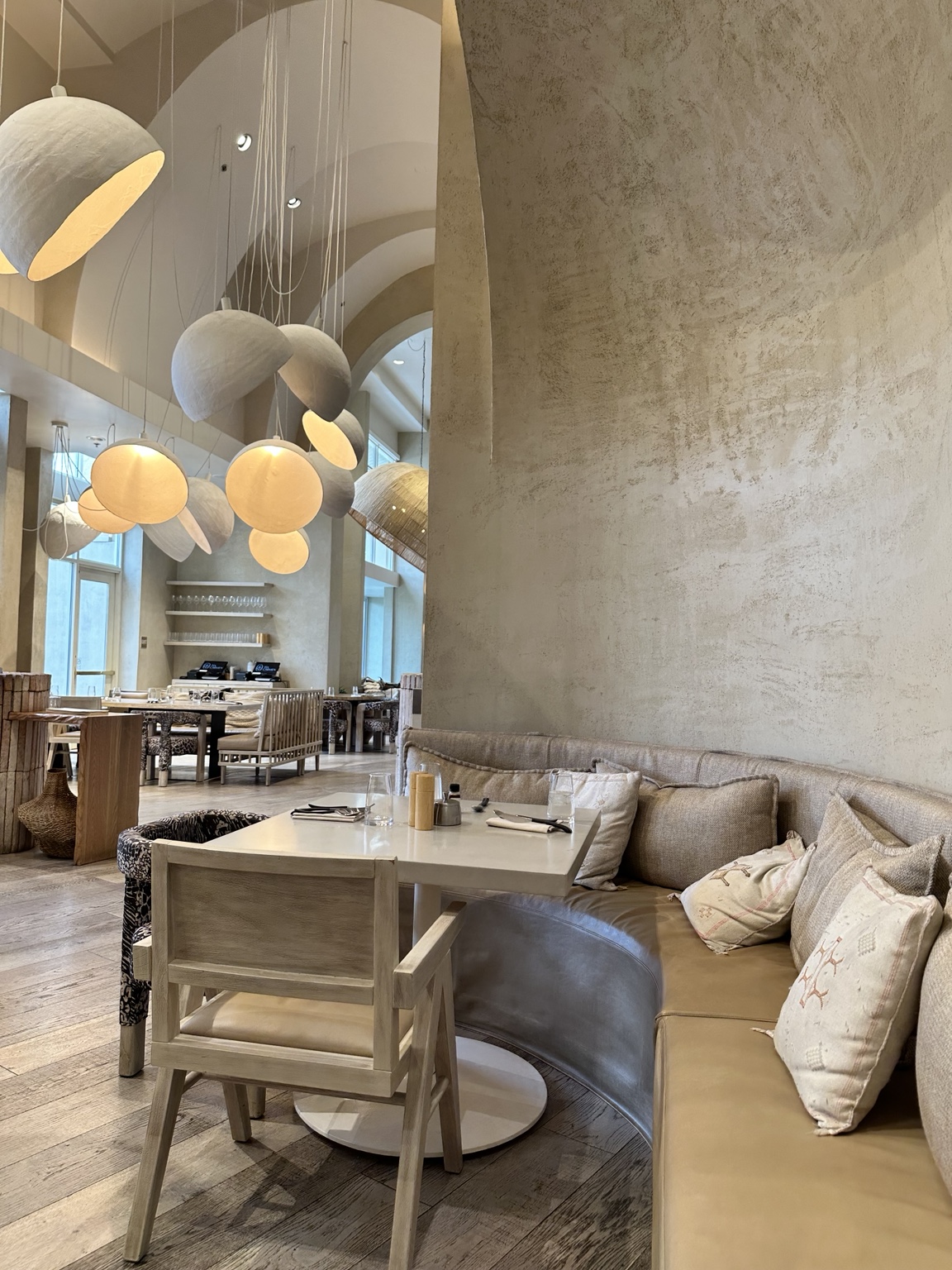 A neutral restaurant interior with sculptural pendant lighting